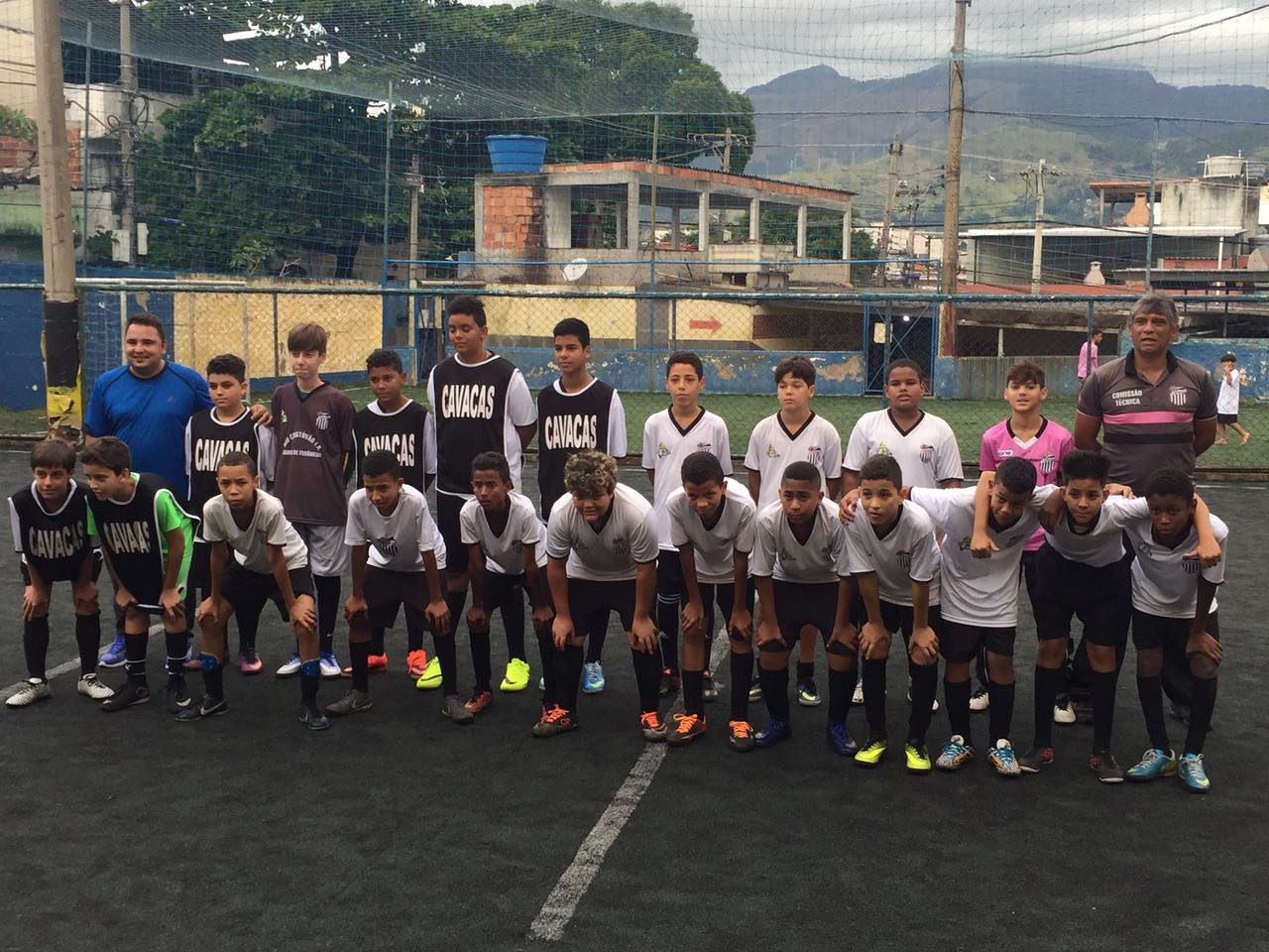 Turma da Escolinha do Tio Alexandre perfilada em campo com vista das montanhas do Rio